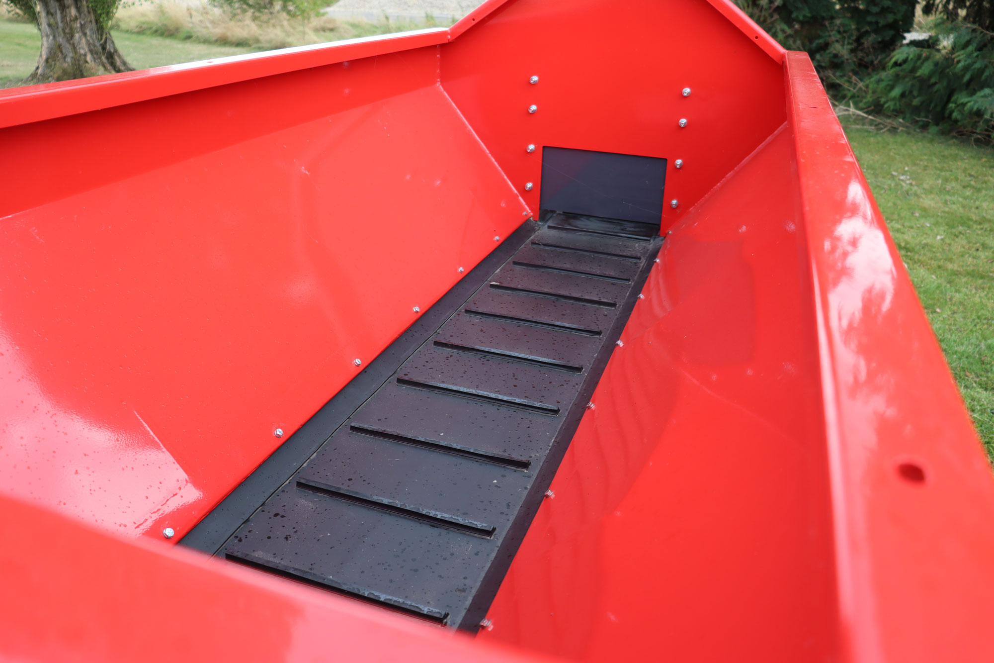 Smooth sided hopper has under-mounted sealing strips which avoid impairing the flow of sand onto the conveyor.